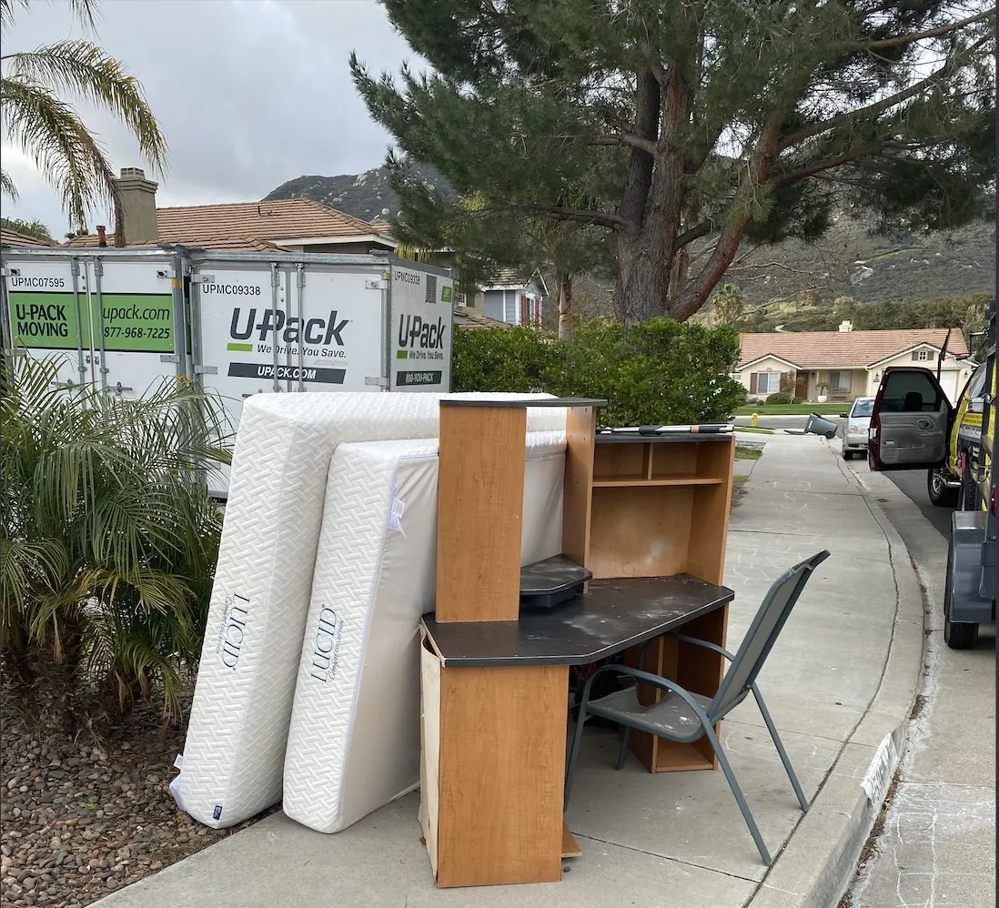 Mattresses and furniture at the curb next to a moving container