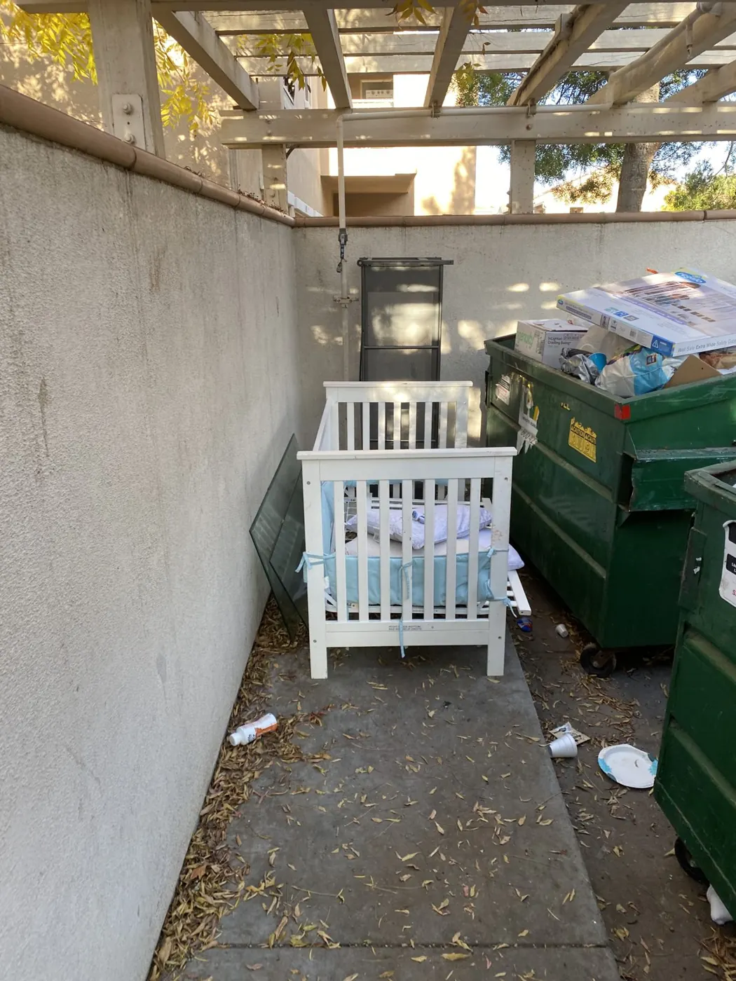 Crib and bulk items dumped at an apartment trash enclosure