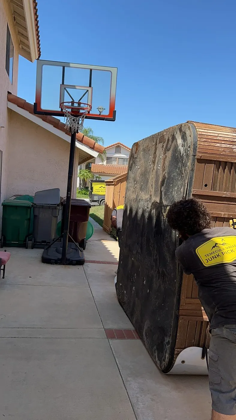 Team moving a hot tub through a side yard