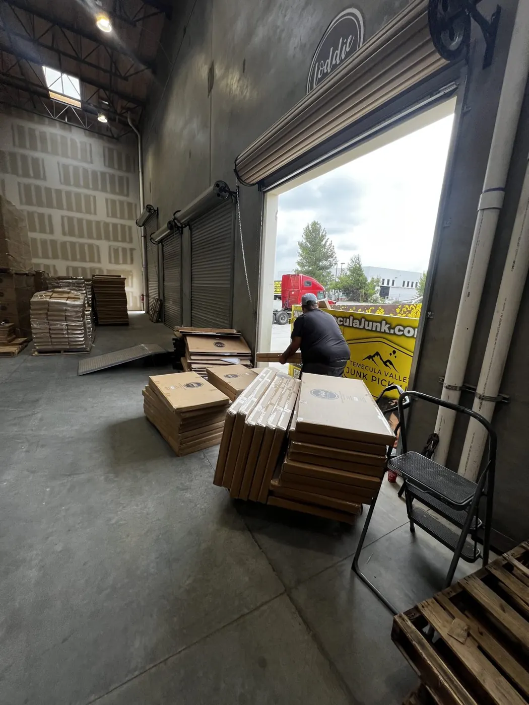 Crew working at a roll-up door with pallets and boxes